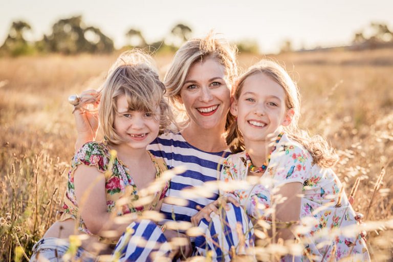 mother and daughters sitting in a field